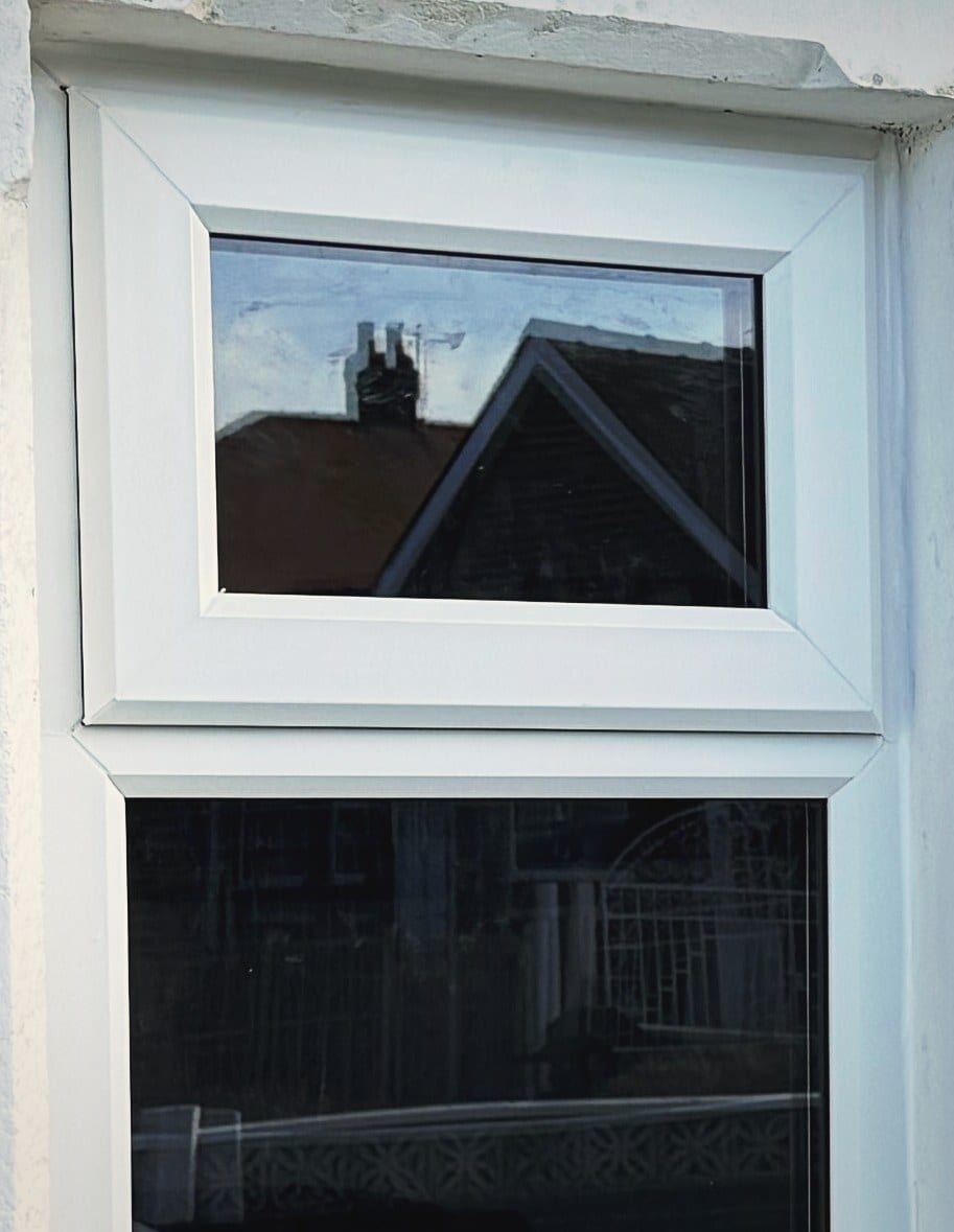 Close view of a white uPVC opening light and its transom, showing the outer seal where the frame meets the stone reveal