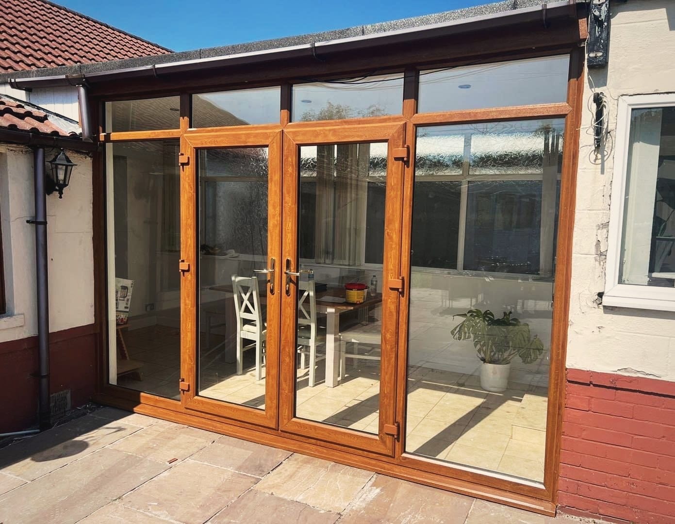 A pair of oak effect French doors with glazed side panels opening onto a patio