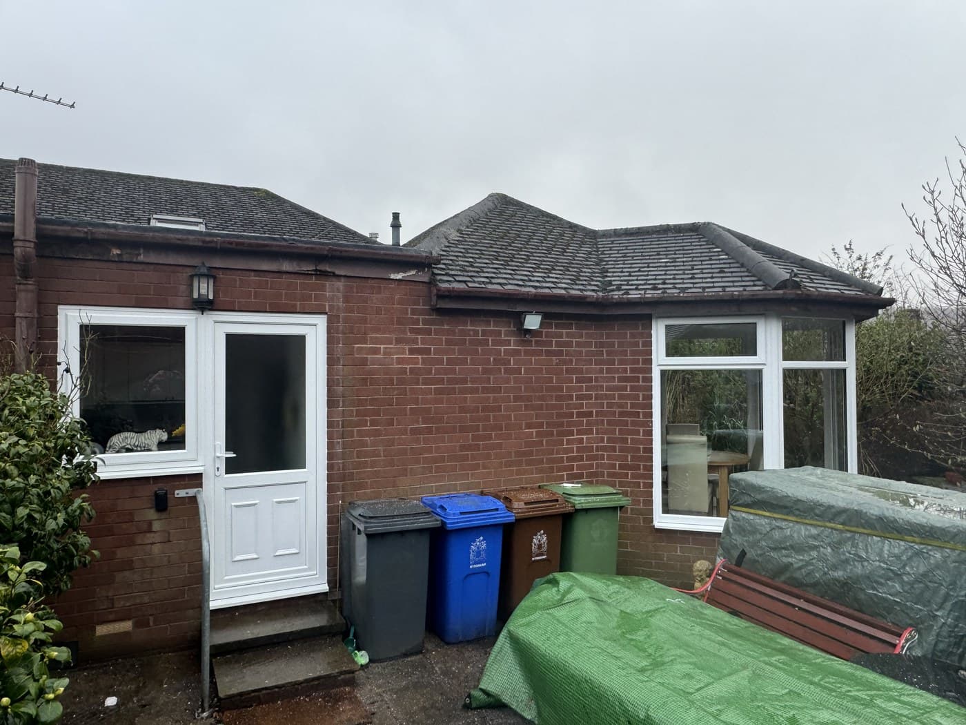 The rear of a red brick bungalow with a new white uPVC door and window