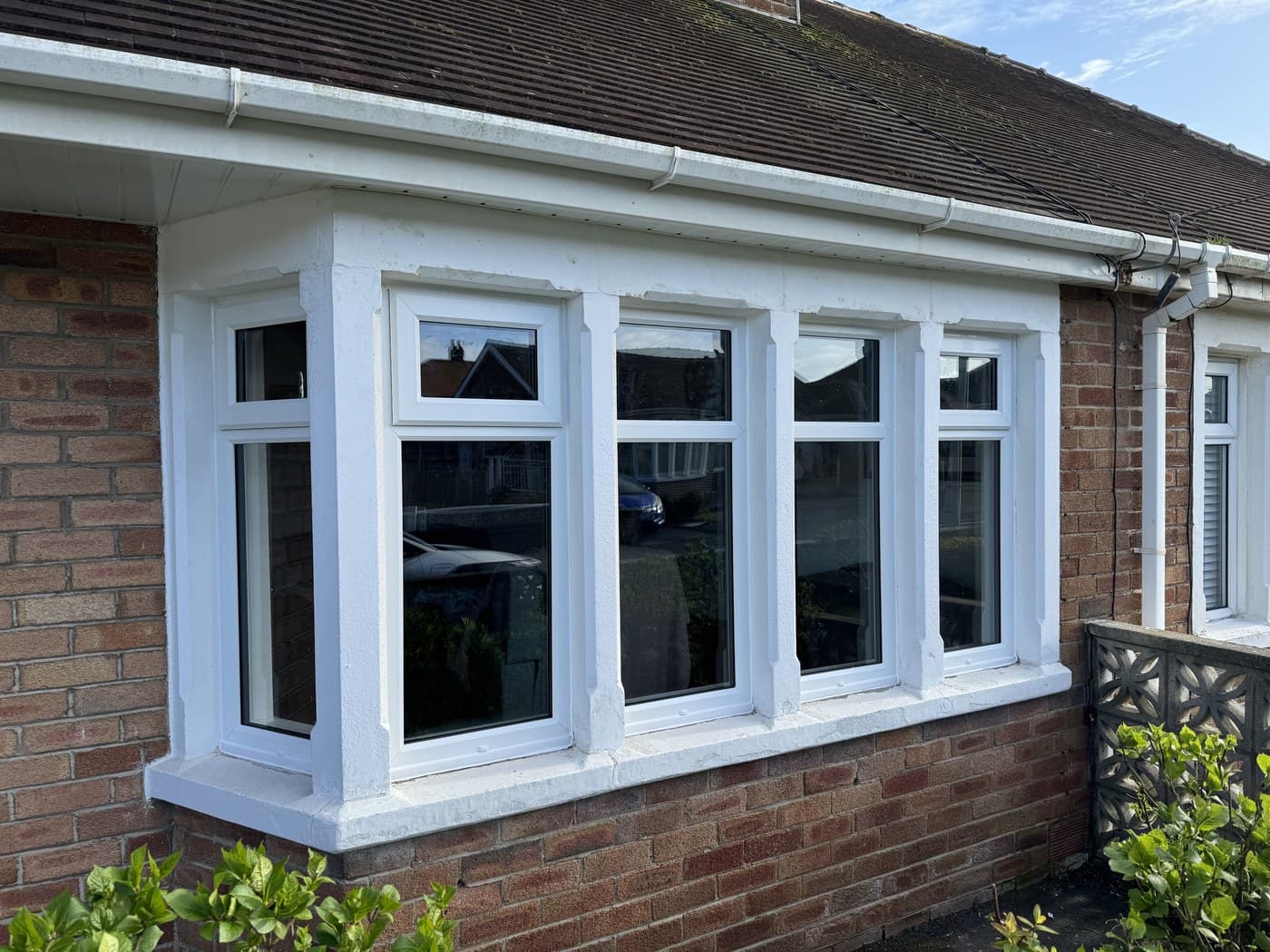 A four pane white uPVC bay window fitted to the front of a brick bungalow