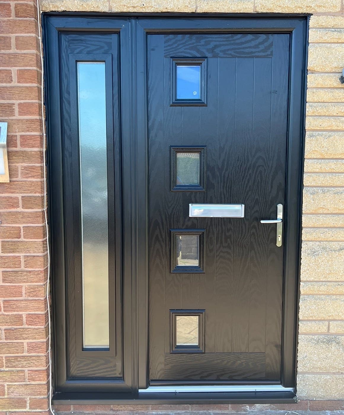 An anthracite composite front door with square glazed panes and a long glazed side panel