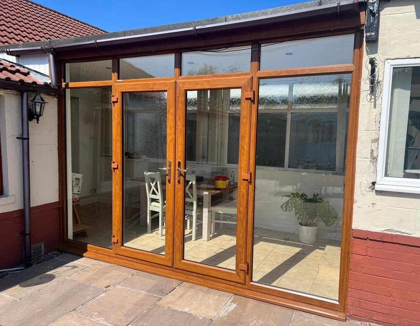 A pair of oak effect uPVC French doors with glazed side panels, opening onto a paved patio