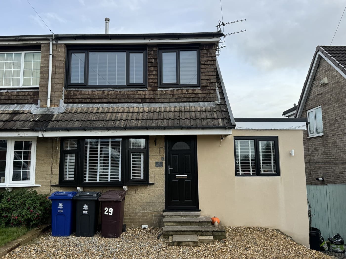 A rendered semi detached house with anthracite uPVC windows and a dark composite front door