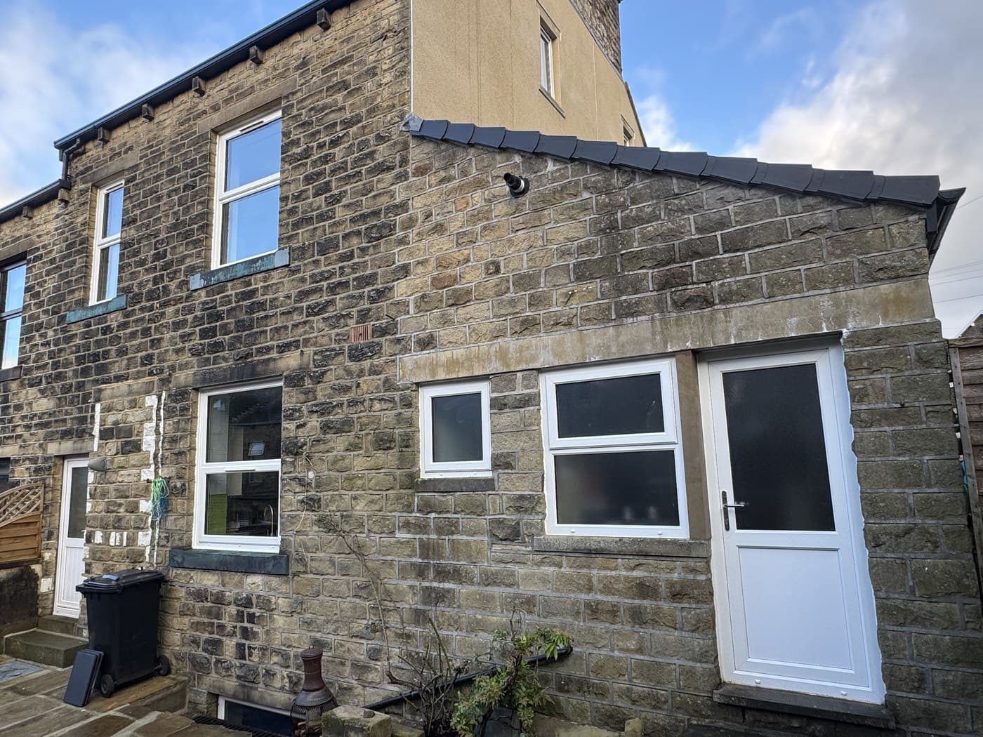 The rear of a stone terrace with new white uPVC windows and a back door