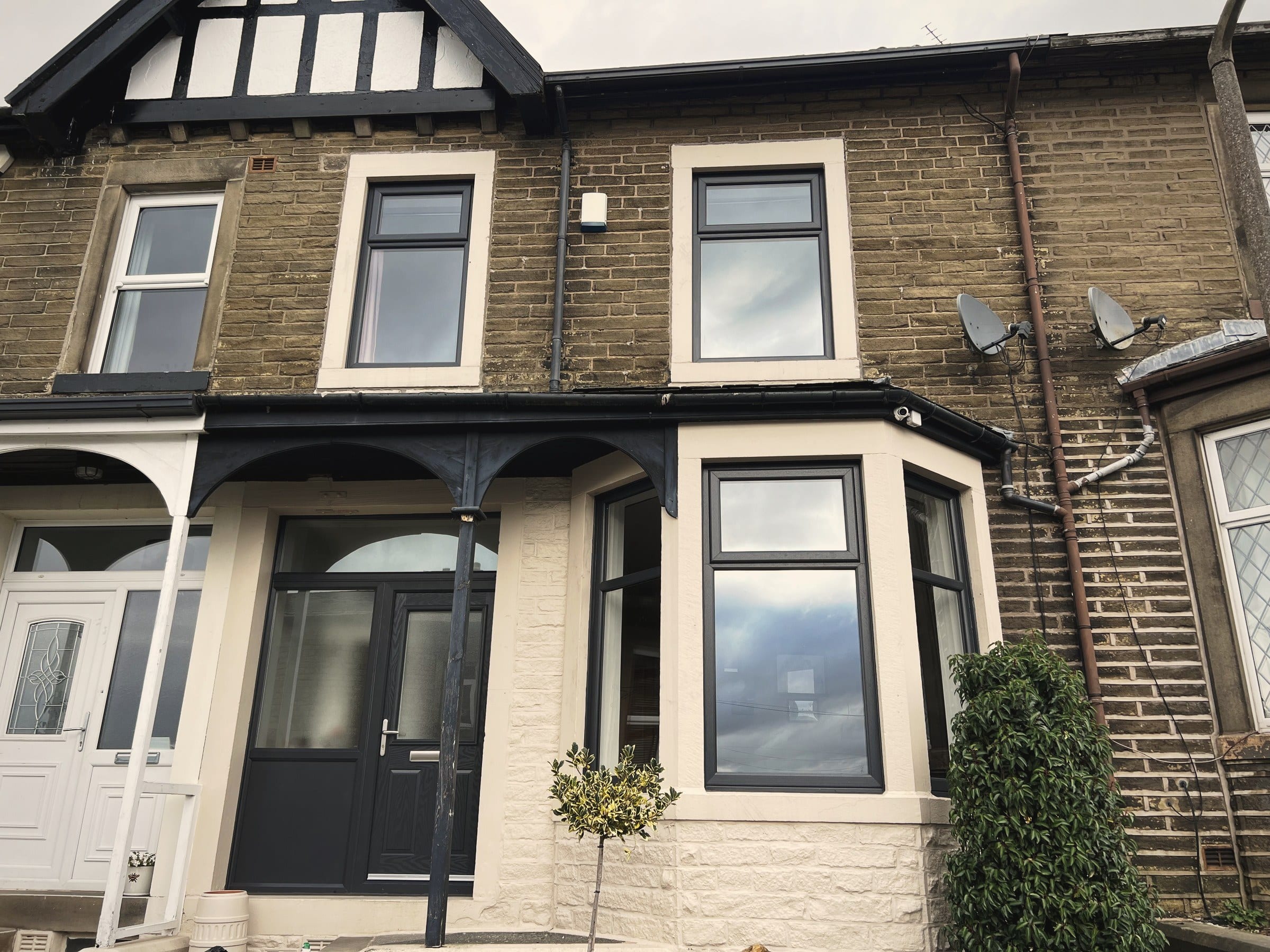 A stone terrace with replacement white uPVC bay windows fitted to the ground and first floors
